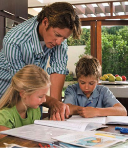Photo of a father reviewing homework with his two children.