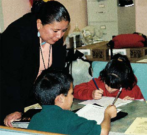 Photo of a teacher helping two clidren in a classroom