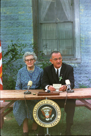 Photo of Lyndon B. Johnson signing the ESEA law next to one of his childhood teachers.