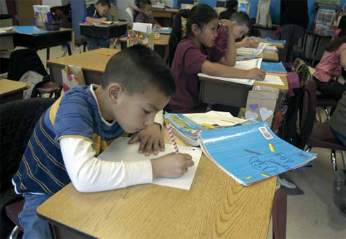 Photo of a boy writing at a desk.