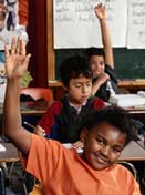 Picture of students in a classroom raising their hands.